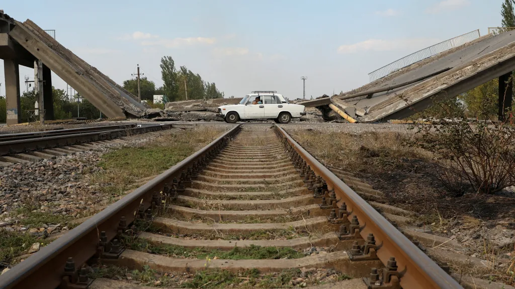 Auto projíždí kolem zničeného pokrovského mostu nad železnicí, 17. září