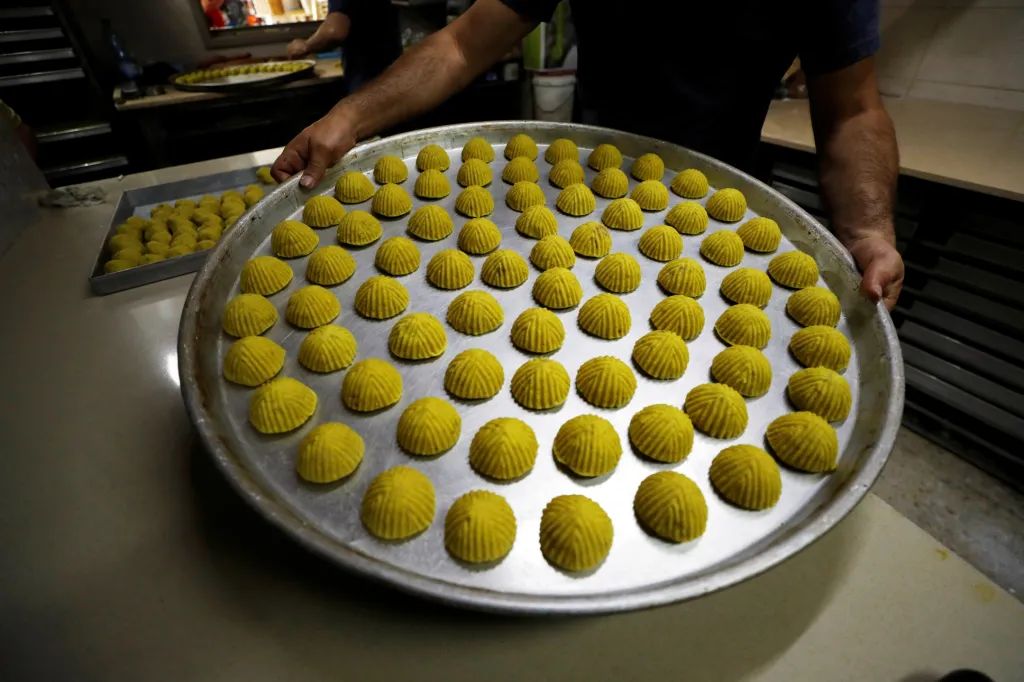 Pracovník pekárny ukazuje tradiční sladkosti, které připravují Palestinci k svátku Íd al-Fitr