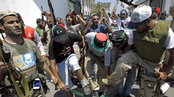 Libyjci šlapou na vlajku Kaddáfího režimu