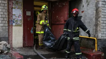 Záchranáři nesou vak s tělem obyvatele, který byl zabit v bytovém domě