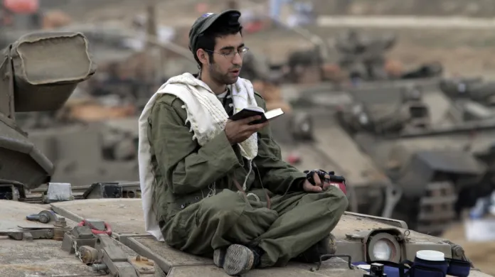 Izraelský voják se modlí na svém tanku poblíž pásma Gazy