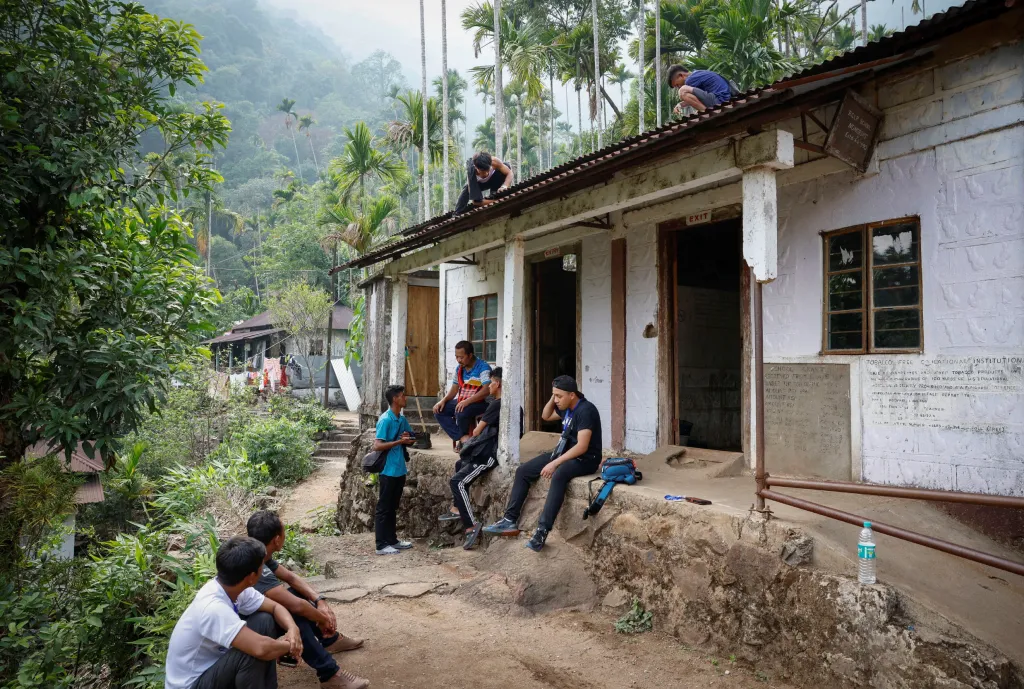 Volební komisaři a nosiči sedí před volební místností po příchodu do vesnice Nongriat