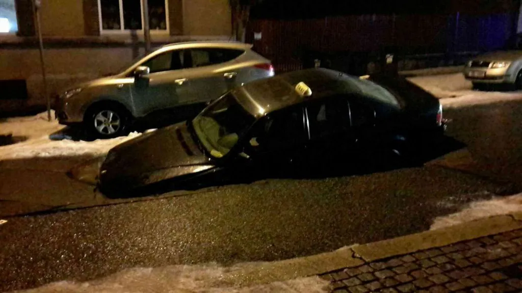 Auto taxislužby uvězněné v propadlé silnici v Chebu