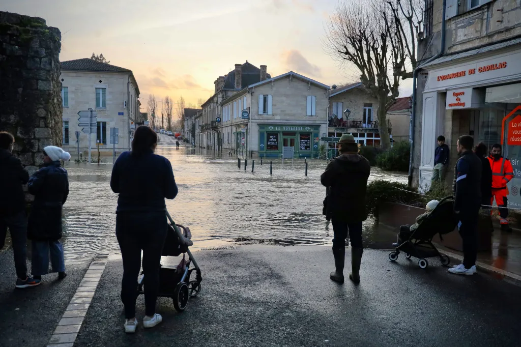 Lidé hledí na zaplavenou ulici ve městě Cadillac-sur-Garonne na západě Francie