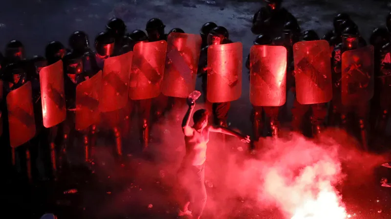 Jeden z demonstrantů hází plastovou láhev na pořádkovou policii v Bukurešti