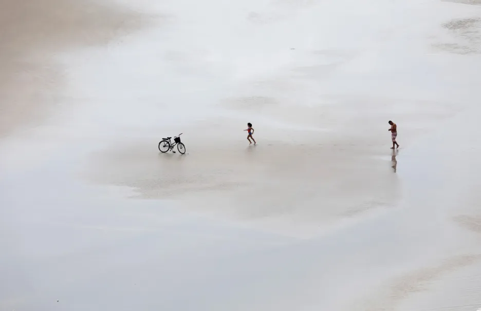 Dívka si běží pro kolo zaparkované na pláži Guaruja v Brazílii
