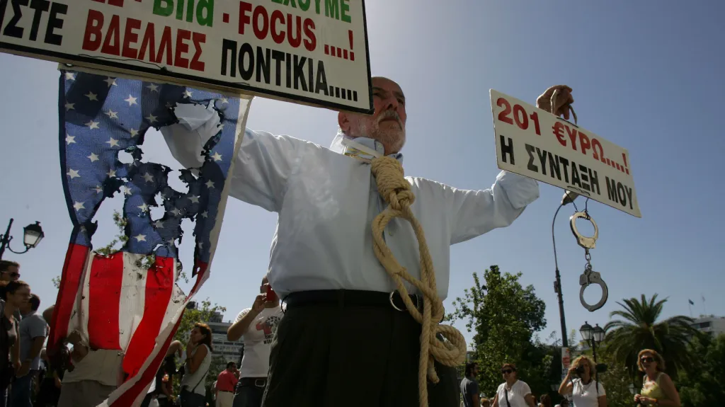 Protestující drží na aténském náměstí Syntagma spálenou americkou vlajku