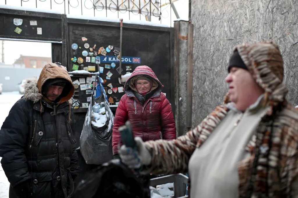 Pracovník recyklačního centra v Omsku váží tašku plnou lahví a hliníkových plechovek, které bezdomovci Saša a Ljusja sesbírali