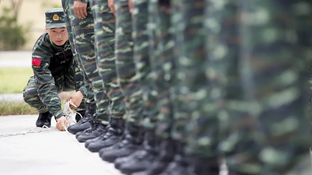 Voják čínské lidové armády zarovnává lanem ostatní vojáky během tréninku na přehlídku