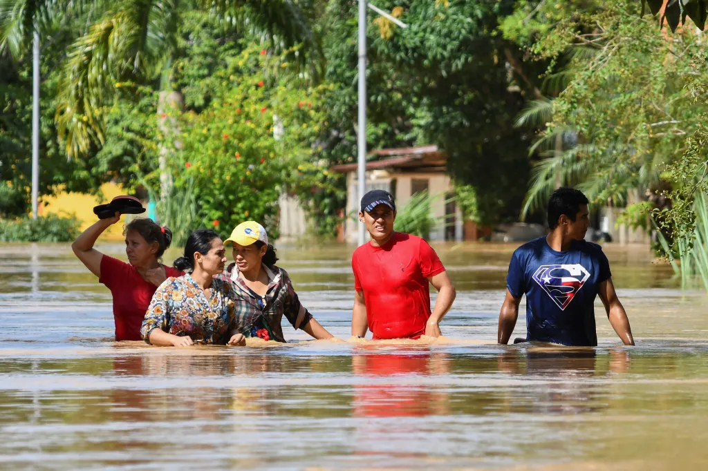 Obyvatelé zatopeného města se brodí ulicí