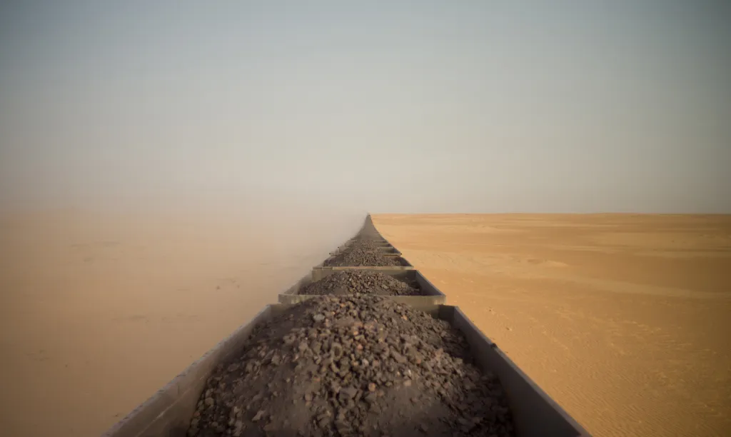 Vítěz kategorie TRAVEL: Riding a Saharan Freight Train. Snímek z vrchu posledního vagonu vlaku s železnou rudou v Mauritánii. Vlak absolvuje 700 kilometrů dlouhou trasu z pobřežního města Nouadhibou do saharské divočiny. Měří až dva a půl kilometru,  veze dvě stovky vagonů kamene a jde o jeden z nejdelších vlaků světa