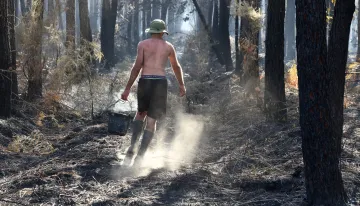 S dohašováním a chlazením půdy ve spáleném lese pomáhají i dobrovolníci s kbelíky vody