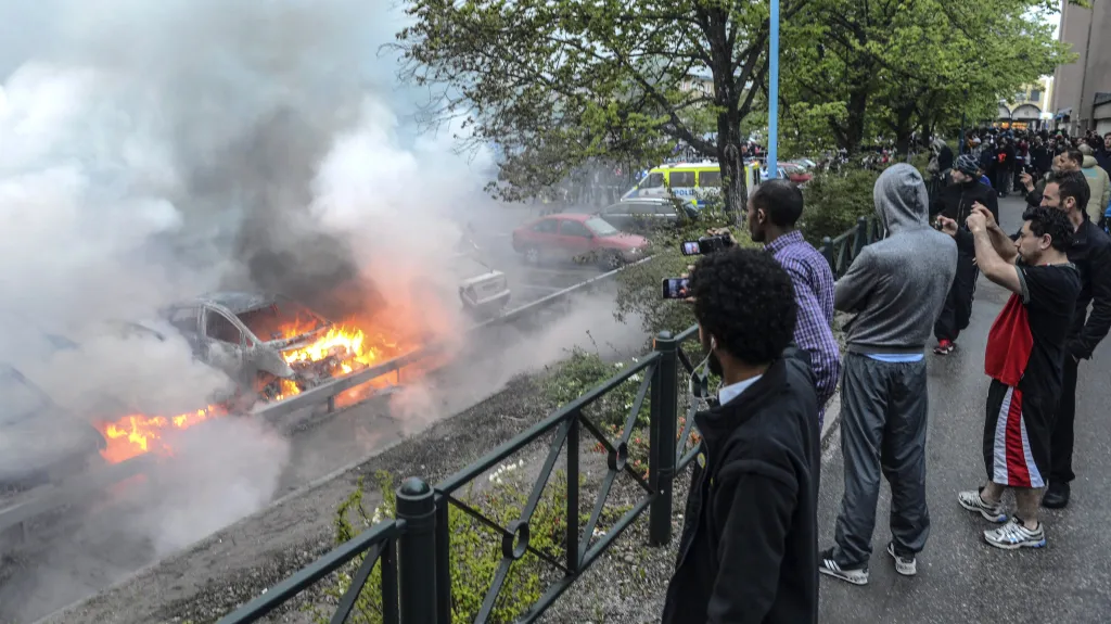 Imigranti sledují zapálená auta na předměstí Stockholmu
