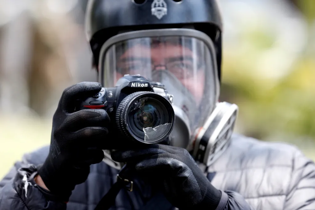 Fotograf se snaží pracovat i poté, co jeho objektiv poškodil projektil vystřelený policií během protestů v Chile