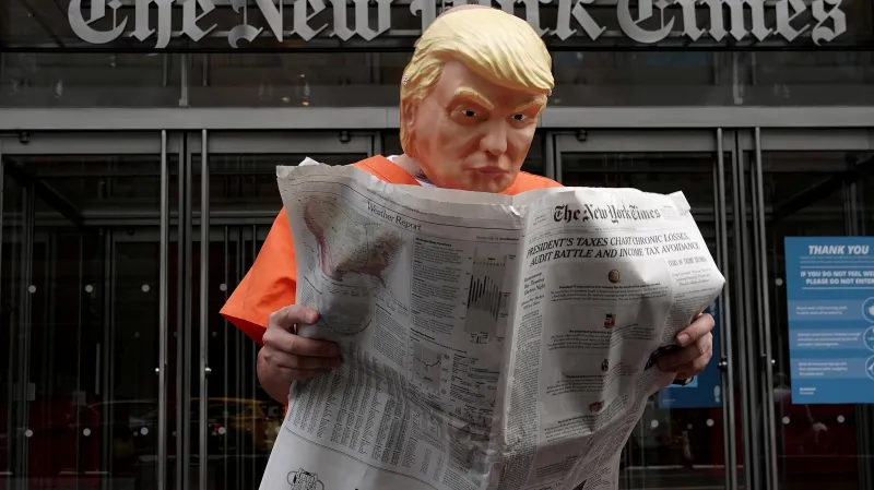Aktivista Mike Hisey čte v masce Donalda Trumpa New York Times