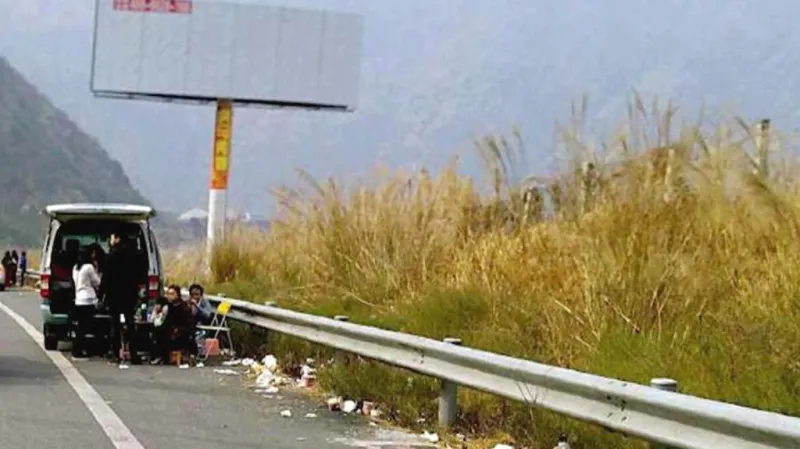 Čínská rodina piknikující na okraji dálnice