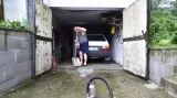 Muž odstraňuje vodu ze zatopené garáže v Černošicích u Prahy