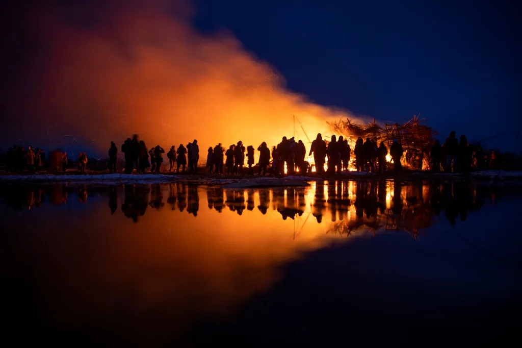 Lidé v ruské vesnici sledují hořící instalaci s názvem „Vakcinační věž“ během oslav Maslenice. Jde o starý pohanský svátek, který je podobný masopustu