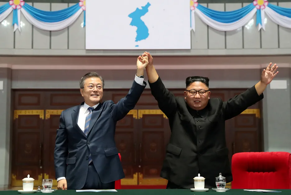 Jihokorejský prezident Mun Če-in a severokorejský vůdce Kim Čong-un zdraví severokorejské publikum před vlajkou sjednocené Koreje po zhlédnutí představení „Slavná země“ na stadionu May Day v Pchjongjangu