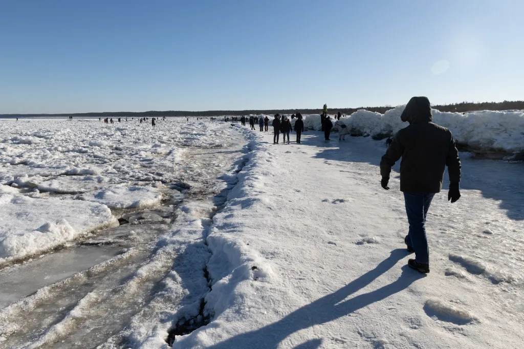 Lidé se prochází po zamrzlém břehu Baltského moře u ústí řeky Visly