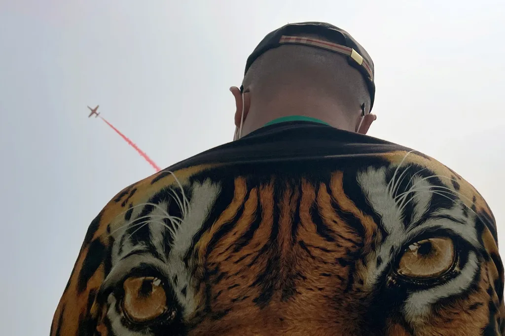 Muž s tygří bundou je fanoušek letectví, který sleduje akrobatický tým Red Falcon na mezinárodním leteckém veletrhu Airshow 2021 v čínském městě Ču-chaj