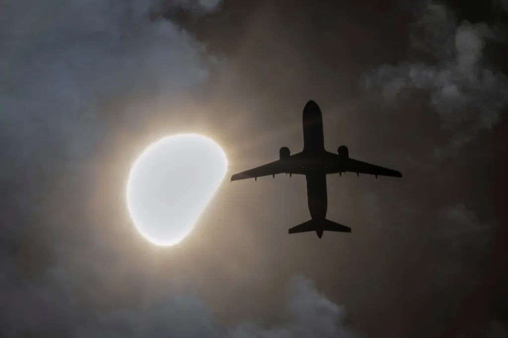 Letadlo letí během částečného zatmění Slunce z Queensu v New Yorku