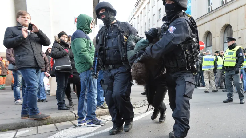 Pochod na podporu Zemana se pokusila zablokovat zhruba desítka lidí sedících na zemi. Policisté je odtáhli do aut.