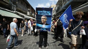 Podporovatel strany Likud drží plakát se svým favoritem na jeruzalémské tržnici