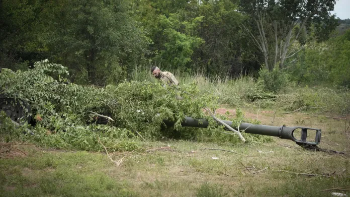 Ukrajinský voják ukrývá v lese houfnici M777 howitzer