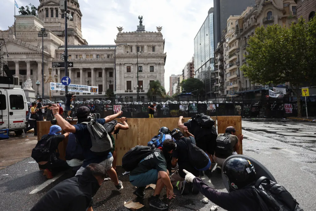 Demonstranti se kryjí za provizorním štítem