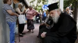 Otec Theoklitos, sedmasedmdesátiletý ortodoxní mnich, čeká spolu s řadou dalších důchodců ve frontě před bankou na to, aby si mohl vybrat malou část svých úspor na důchod.