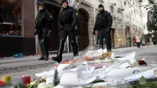 Policejní hlídka prochází kolem květin položených na místě úterního útoku