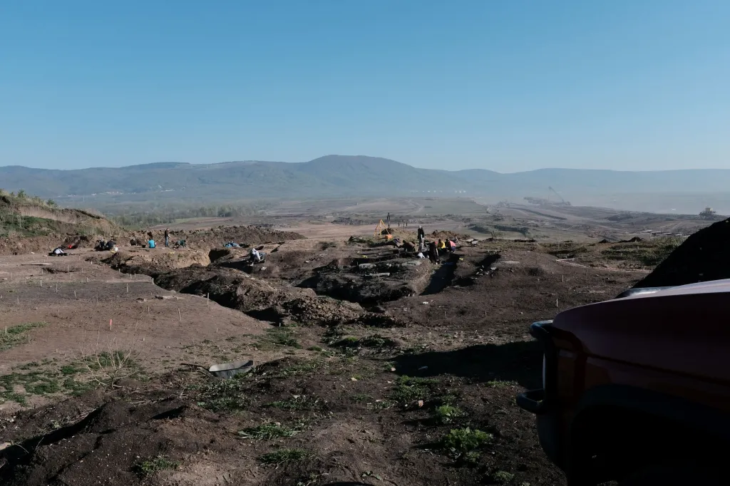 Archeologický výzkum raně středověkého pohřebiště. Zhruba uprostřed se nacházel kostelík a ještě jedna větší sakrální stavba, jejíž určení není zatím známé. V dálce pod horami je vidět město Osek
