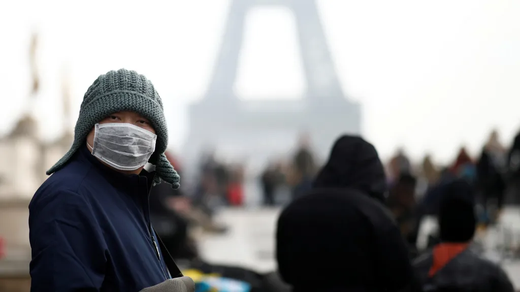 Číňan s maskou před Eiffelovou věží v Paříži