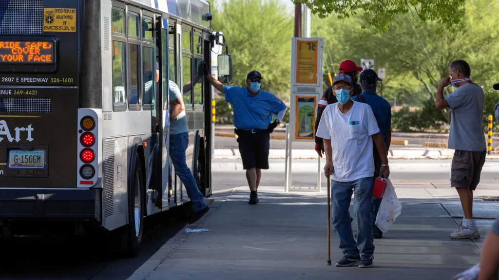 Lidé s rouškami na zastávce autobusu v arizonském městě Tucson