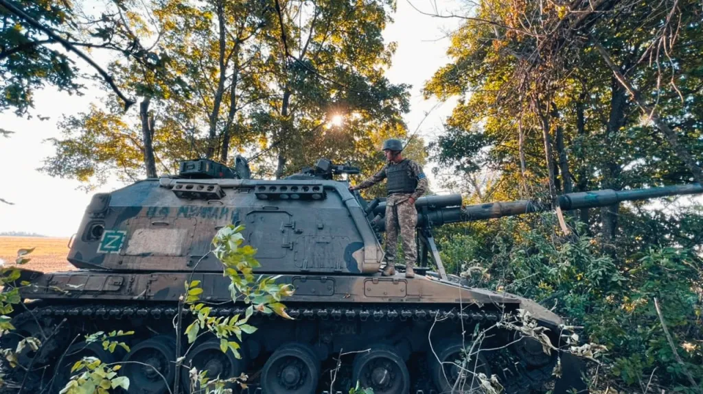 Ukrajinský voják stojí na zabavené ruské houfnici v Charkovské oblasti