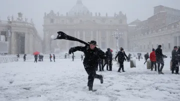 Mladý mnich při koulování čerstvým sněhem na Svatopetrském náměstí ve Vatikánu