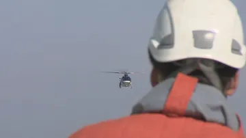 Záchranář vyhlíží ze střechy AZ toweru vrtulník