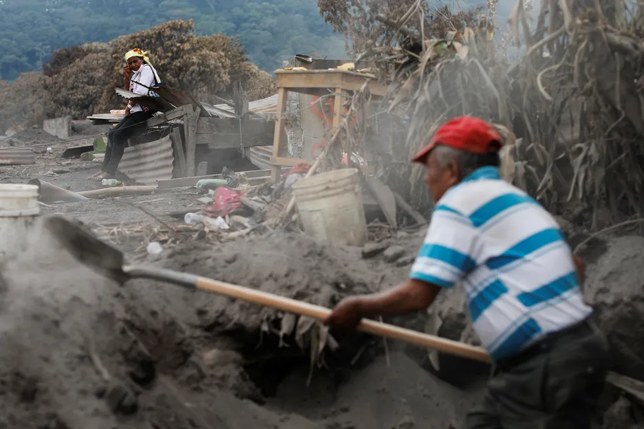 Eufemia Garcia (48 let), která po erupcích sopky Fuego ztratila 50 členů své rodiny, pozoruje dobrovolníka, který pomáhá pátrat po dalších obětech neštěstí ve vesnici San Miguel Los Lotes v Guatemale