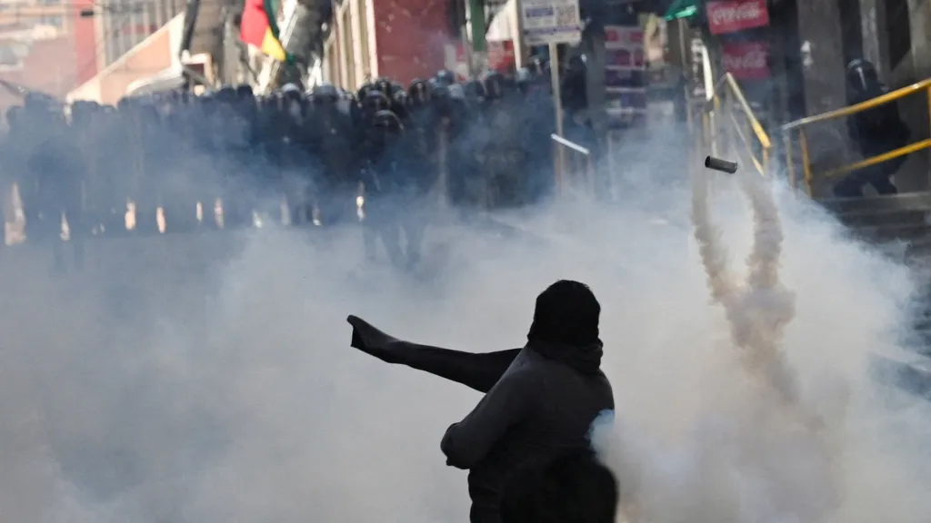 Jeden z demonstrantů hází směrem k policii kanystr se slzným plynem