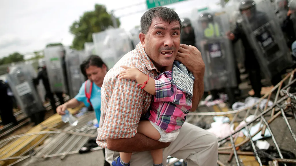 Migrant z Hondurasu chrání své dítě během násilných střetů s policií, když se skupina migrantů z karavany mířící k hranicím USA pokusila prolomit hraniční bariéry z Guatemaly do Mexika ve městě Hidalgo.