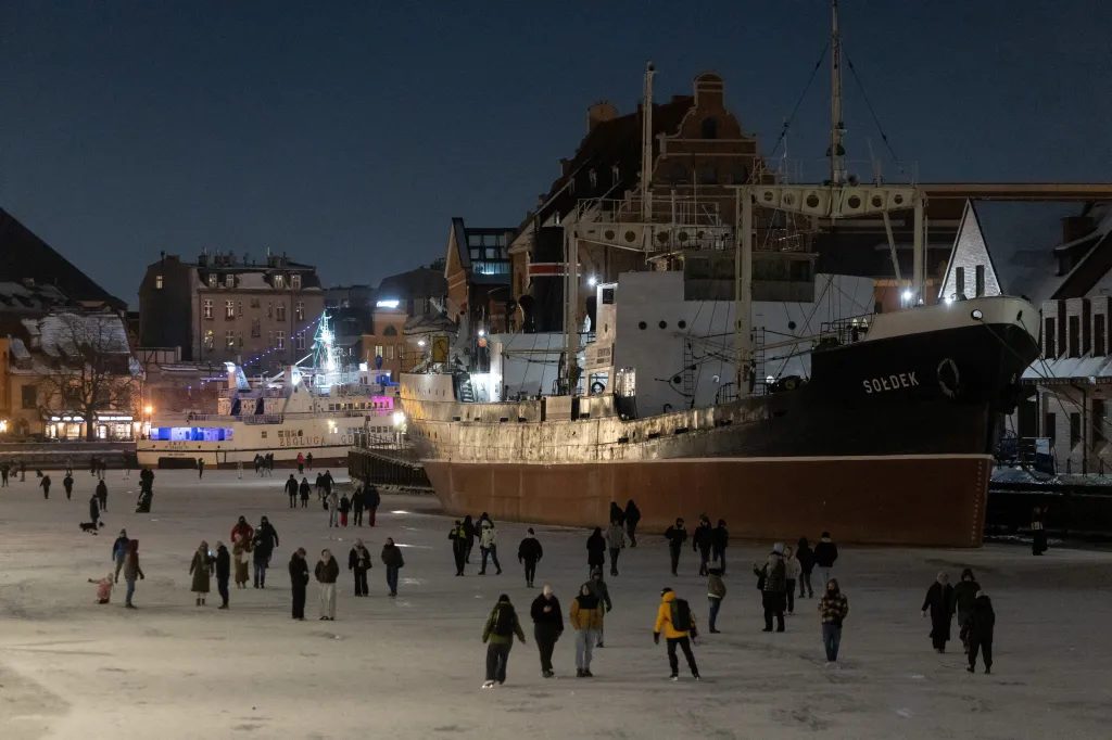 Lidé se procházejí a bruslí na zamrzlé řece Motlawě v polském Gdaňsku