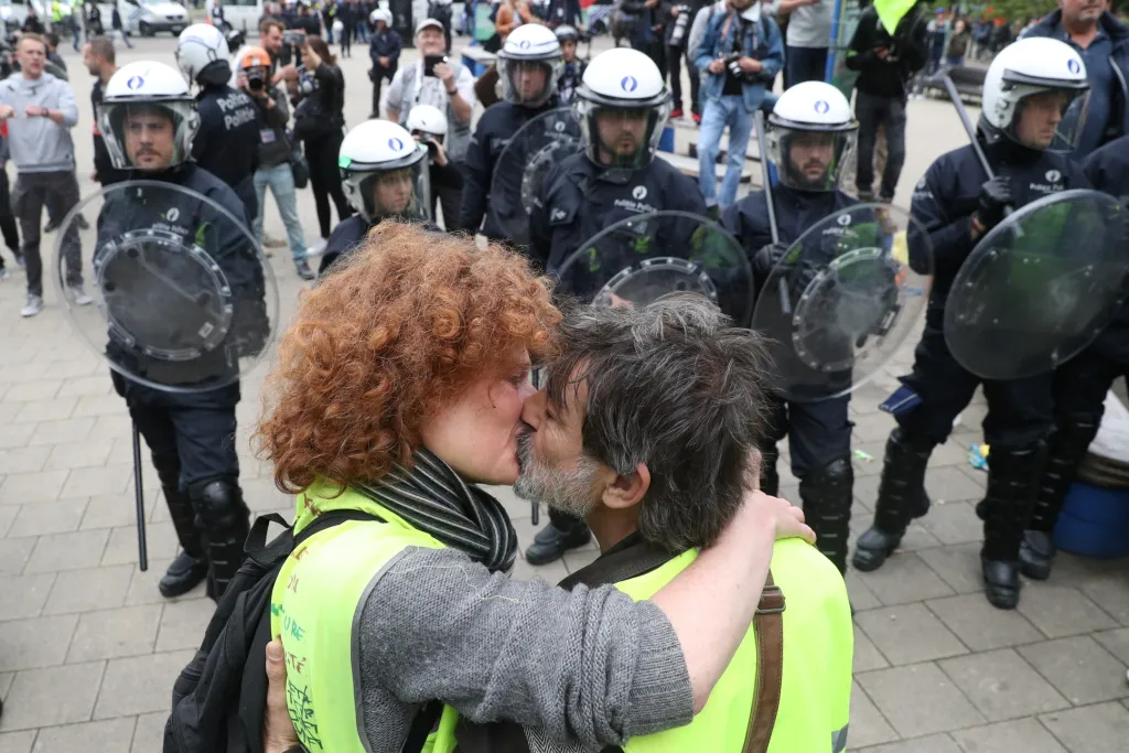 Protestující ze skupiny „žlutých vest“ se líbají před skupinou policistů, která chrání Evropský parlament v Bruselu (26. května 2019)
