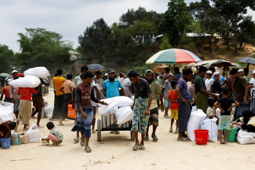 Rohingští uprchlíci nesou pytle s rýží z potravinové pomoci od Světového potravinového programu (WFP) v uprchlickém táboře