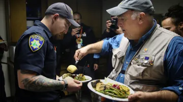 Jose Andres, ředitel a zakladatel organizace World Central Kitchen, podává talíř s porcí slavnostní večeře četníkovi policejní stanice města Paradise, které zničil nedávný požár v Kalifornii