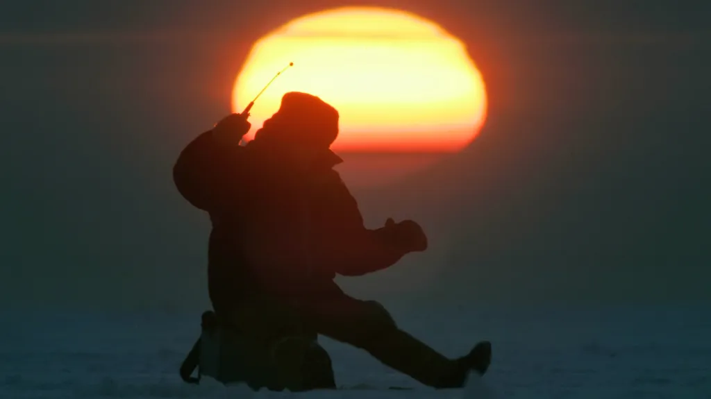 Rybář v zimě v zamrzlém Finském zálivu
