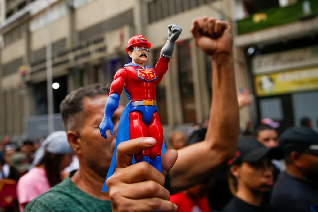 Účastník pochodu drží figurku prezidenta Nicoláse Madura v obleku superhrdiny