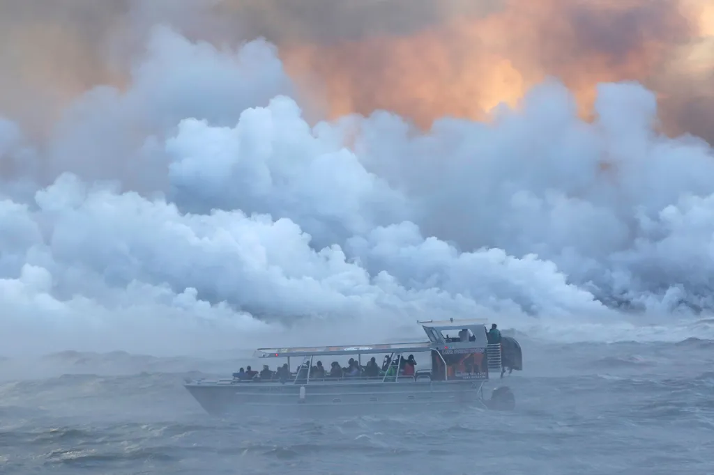 Turisté ve vyhlídkové lodi sledují, jak se láva z havajského vulkánu Kilauea se syčením a pod oblaky toxických par vlévá do vod Tichého oceánu