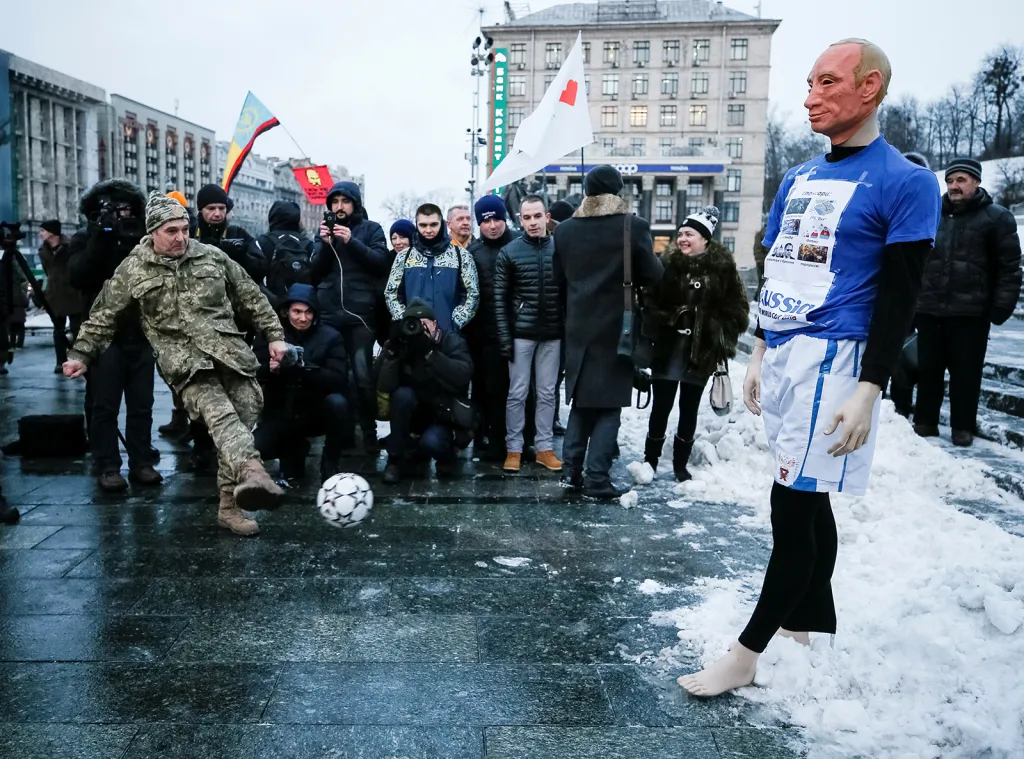 Ukrajinský voják nahrává míč figurině Vladimíra Putina ve fotbalovém dresu během demonstrace v centru Kyjeva proti Rusku jako pořadateli světového šampionátu ve fotbale 2018