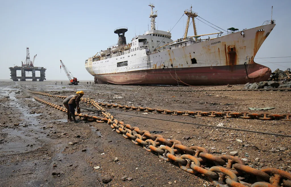 Dělníci táhnou lano připoutané k vyřazené ropné plošině v loděnici Alang v indickém státě Gujarat.